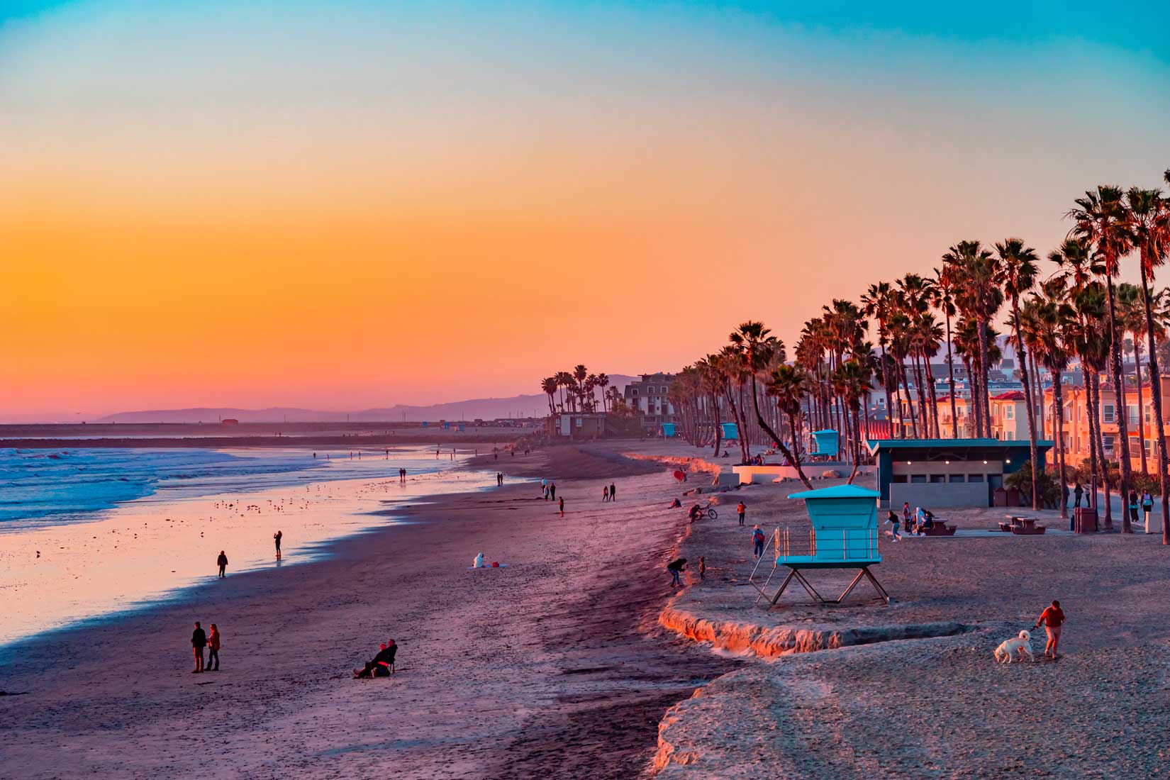 A Oceanside sunset at the beach draws people to it to walk and r